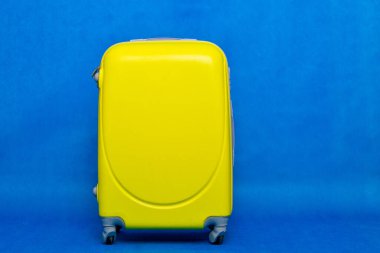 Seyahat çantası duvara. Mavi arka planda sarı bavul..