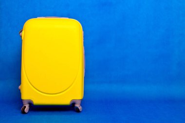 Seyahat çantası duvara. Mavi arka planda sarı bavul..