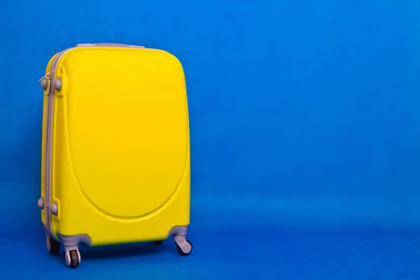 stock image Travel bag to the wall. Yellow suitcase on a blue background.