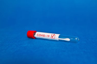 Üzerinde COVID-19 yazan mavi bir arkaplanda burun tamponu testi..