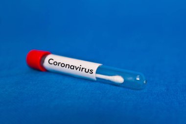 Mavi arkaplandaki burun tamponu testinde koronavirüs yazılıydı.