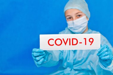 Genç doktor covid-19 yazan bir tabela gösteriyor..