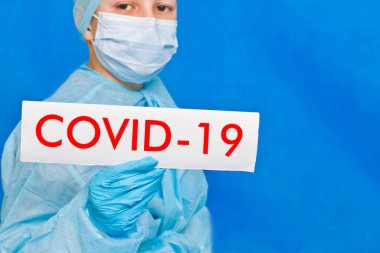 Genç doktor covid-19 yazan bir tabela gösteriyor..