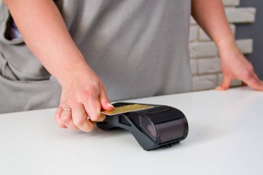 Kredi kartı terminaline ödeme yapmak için kart iliştiren bir kadının yakın çekimi. Ödeme prosedürü