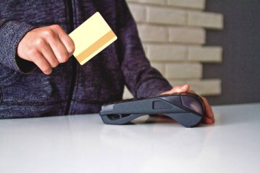 Delikanlının elleri ödeme terminalinde bir kartla tutuluyor..