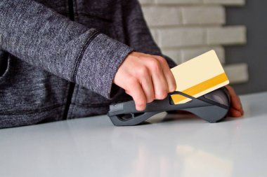 Delikanlının elleri ödeme terminalinde bir kartla tutuluyor..