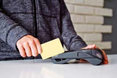 Delikanlının elleri ödeme terminalinde bir kartla tutuluyor..