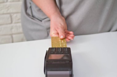 Kredi kartı terminaline ödeme yapmak için kart iliştiren bir kadının yakın çekimi. Ödeme prosedürü