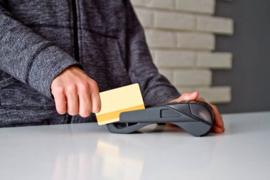 Delikanlının elleri ödeme terminalinde bir kartla tutuluyor..