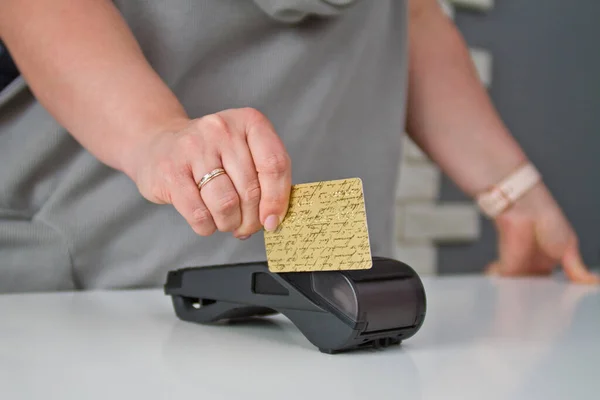 A female hand holds a card through the terminal to pay for the goods.
