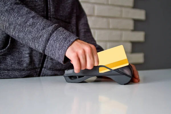 Delikanlının elleri ödeme terminalinde bir kartla tutuluyor..