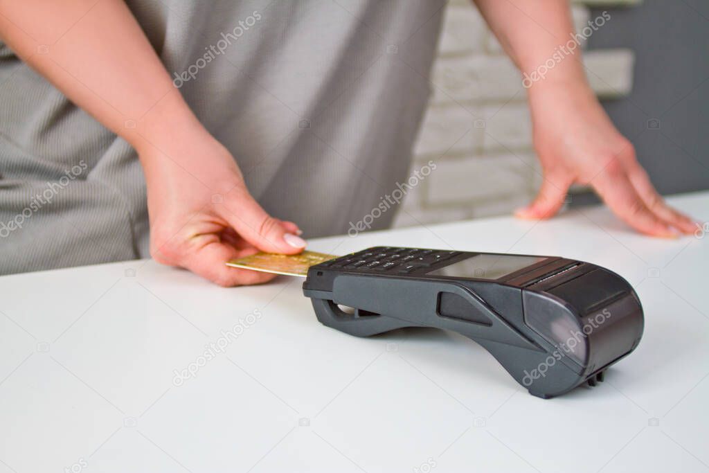 Close-up of a woman attaching a card to a credit card terminal to secure payment. Payment procedure