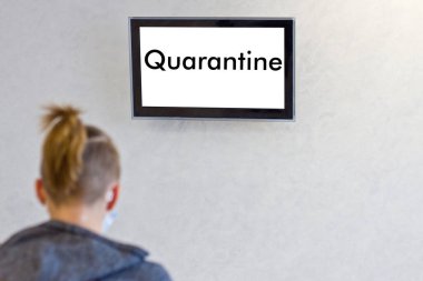 Adamlar ellerinde karantinayla televizyonun önünde oturuyorlar.