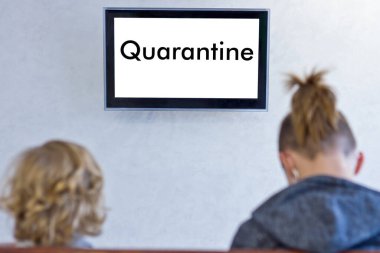 Adamlar ellerinde karantinayla televizyonun önünde oturuyorlar.