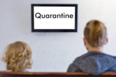 Adamlar ellerinde karantinayla televizyonun önünde oturuyorlar.