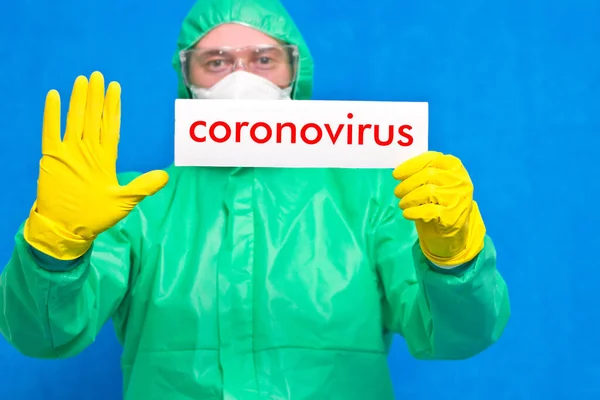 白いポスターにコロナウイルスの文字が入った医療従事者が青い背景に立っている — ストック写真