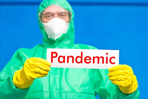 Pracownik Medyczny Trzymający Biały Plakat Napisem Pandemia Stojący Niebieskim Tle — Zdjęcie stockowe
