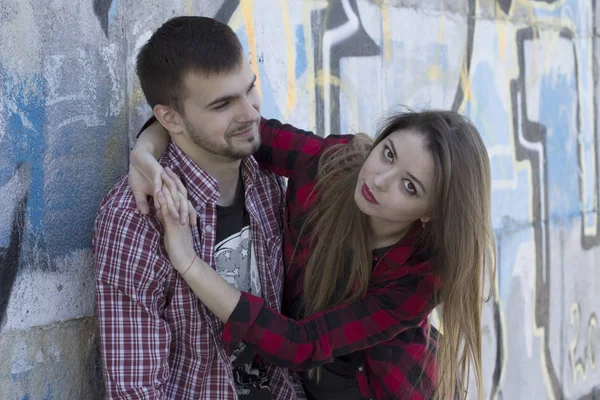 Chica joven abraza a su novio cerca de la pared de graffiti. Historia de amor. Día de San Valentín — Foto de Stock
