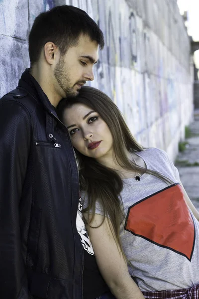Junger Mann umarmt seine Freundin in der Nähe von Graffiti-Wänden. Liebesgeschichte. Valentinstag — Stockfoto