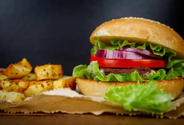 Hamburguesa grande con papas fritas en la oscuridad — Foto de Stock