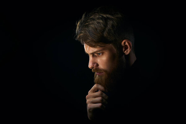 Крупным планом портрет озадаченного молодого человека, трогающего бороду глядя делать

