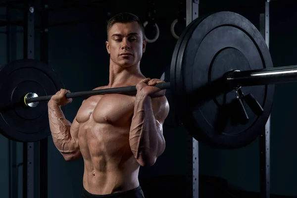 Svart och vit närbild foto av man gör en lyftande träning på mörk bakgrund på gym. — Stockfoto