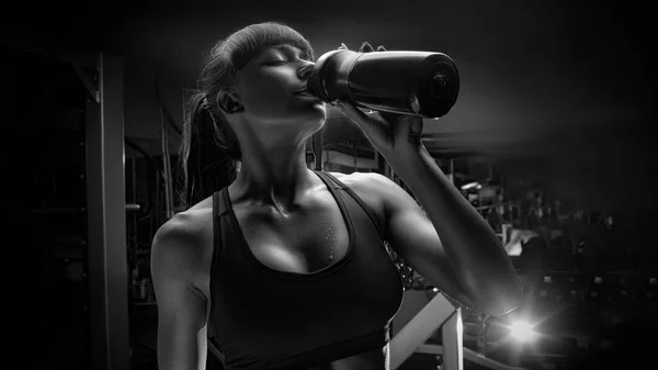 Черно-белое фото фитнес-женщины, пьющей воду из бутылки — стоковое фото