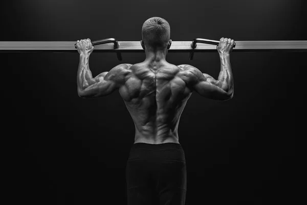 Power muscular bodybuilder guy doing pullups in gym. Fitness man — Stock Photo, Image