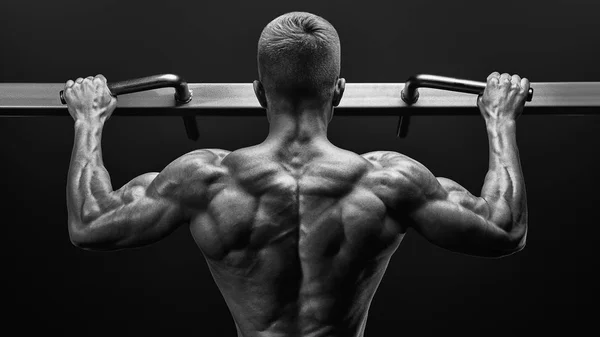 Power muscular bodybuilder guy doing pullups in gym. Fitness man — Stock Photo, Image
