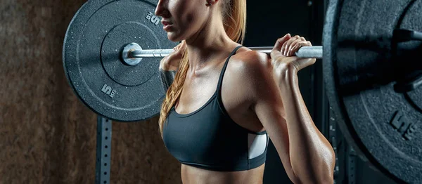 Mujer culturista haciendo sentadillas en el gimnasio —  Fotos de Stock