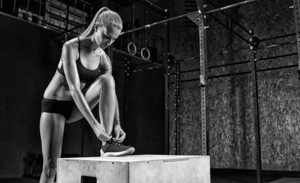 Mujer de fitness atando zapatillas en el gimnasio —  Fotos de Stock