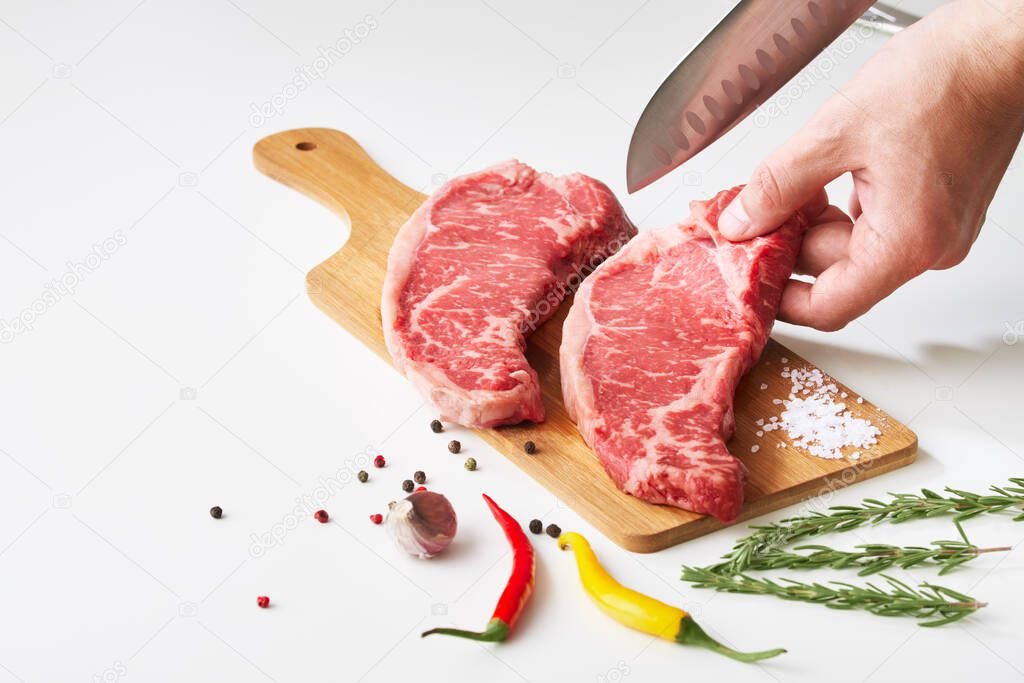 Chef slicing raw meat steak on wooden board