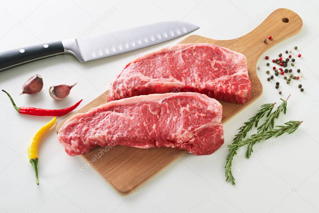 Two fresh raw striploin steak on wooden board