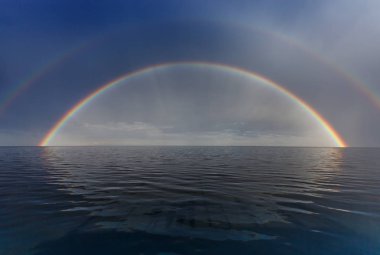 Mavi gökyüzü ve bir gökkuşağının üstünde küçük kumlu dere Plajı