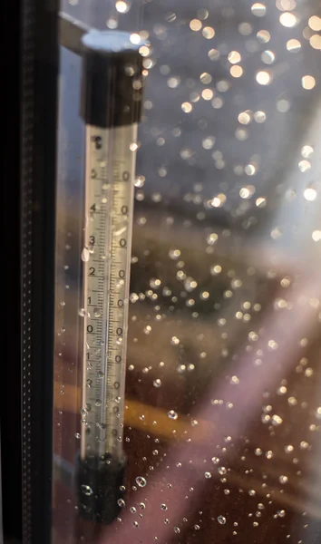 落在温度温度计的规模。滴的雨水一场暴风雨后的窗口。水在玻璃上滴雨后. — 图库照片