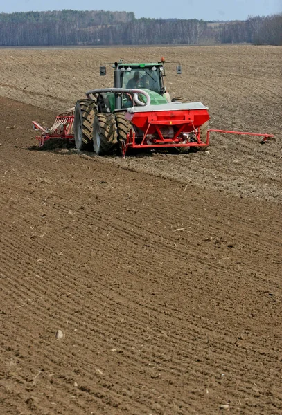 Traktor bereitet Land für die Aussaat vor. Traktor mit Grubber bearbeitet Feld vor der Pflanzung. Land für die Aussaat im Frühjahr vorbereiten, Bauer im Traktor. — Stockfoto