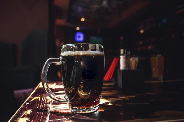 Verre de bière sur table en bois marron sur fond sombre. Verre de bière sur une table . — Photo