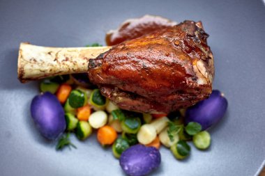 Domuz knuckle patates ve salata, üstten görünüm ile bir tavada kavrulmuş. Kırmızı şarap soslu sebzeli kuzu eklemleri.