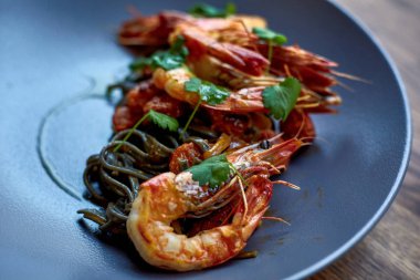 Pişmiş karides, karides ile baharat üzerinde arka plan taş. Kızarmış karides alakart bir tavada bir karanlık masa üstü üzerinde rosemary ile görüntüleyin. Karides restoranda kiraz domates ile dökme demir tava üzerinde. 