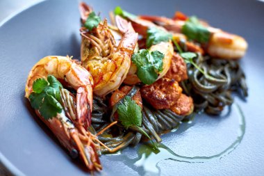 Pişmiş karides, karides ile baharat üzerinde arka plan taş. Kızarmış karides alakart bir tavada bir karanlık masa üstü üzerinde rosemary ile görüntüleyin. Karides restoranda kiraz domates ile dökme demir tava üzerinde. 