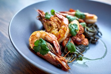 Pişmiş karides, karides ile baharat üzerinde arka plan taş. Kızarmış karides alakart bir tavada bir karanlık masa üstü üzerinde rosemary ile görüntüleyin. Karides restoranda kiraz domates ile dökme demir tava üzerinde. 