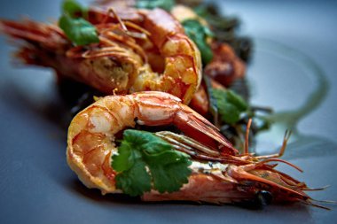 Pişmiş karides, karides ile baharat üzerinde arka plan taş. Kızarmış karides alakart bir tavada bir karanlık masa üstü üzerinde rosemary ile görüntüleyin. Karides restoranda kiraz domates ile dökme demir tava üzerinde. 