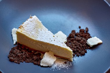 Dilimlenmiş New York Cheesecake beyaz tabakta ahşap arka planda