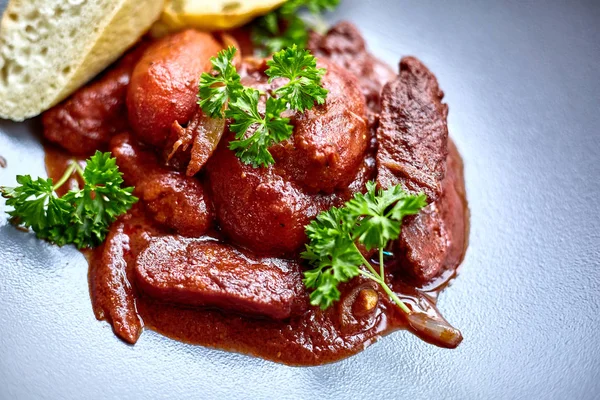 warm salad with chicken liver and grapes on the white plate. Warm salad from turkey liver. Warm salad with chicken liver in raspberry sauce.