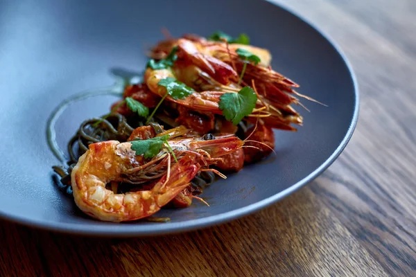 Cooked shrimps,prawns with seasonings on stone background. Fried shrimp with rosemary in a portioned frying pan on a dark table top view. Shrimps on a cast iron skillet with cherry tomatoes in the restaurant. — Stock Photo, Image
