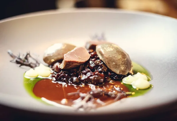 warm salad with chicken liver and grapes on the white plate. Warm salad from turkey liver. Warm salad with chicken liver in raspberry sauce.