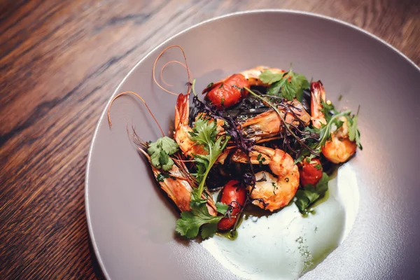 Cooked shrimps,prawns with seasonings on stone background. Fried shrimp with rosemary in a portioned frying pan on a dark table top view. Shrimps on a cast iron skillet with cherry tomatoes in the restaurant. — Stock Photo, Image