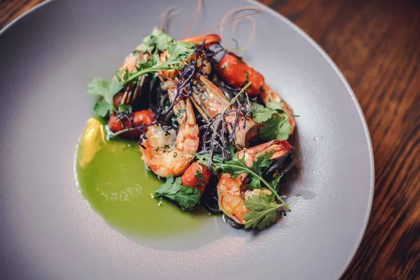 Cooked shrimps,prawns with seasonings on stone background. Fried shrimp with rosemary in a portioned frying pan on a dark table top view. Shrimps on a cast iron skillet with cherry tomatoes in the restaurant. — Stock Photo, Image