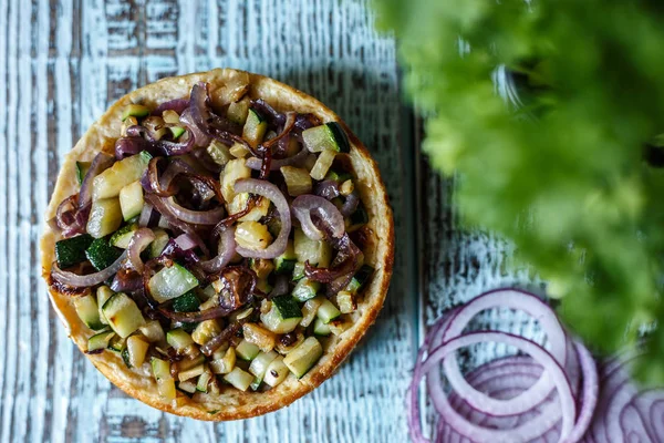 Avustralya et pasta tablo ve soğan ve avokado üzerinde yatay bir üstten görünüm, rustik tarzı. Ahşap masa portre üzerinde ev yapımı Avustralya etli börek. Lezzetli bir plaka üzerinde et pastası kesti. Amerikan Tavuklu paçanga böreği masaya pişirme çanağı içinde. — Stok fotoğraf