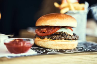 Siyah arka planda izole edilmiş ahşap masada sığır burger ve patates kızartması. Tahta tepside hamburger ve patates kızartması..